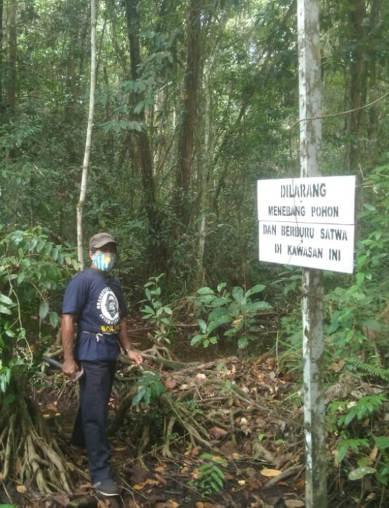 OFI ranger placing sign: “It is forbidden to cut trees and hunt animals in this area.”